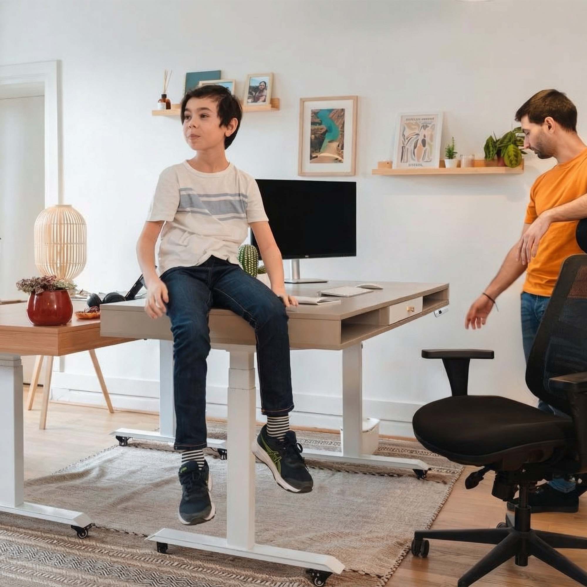 Enfant assis sur le plateau d'un bureau assis-debout KQUEO Space Dynamique avec pieds blancs.
