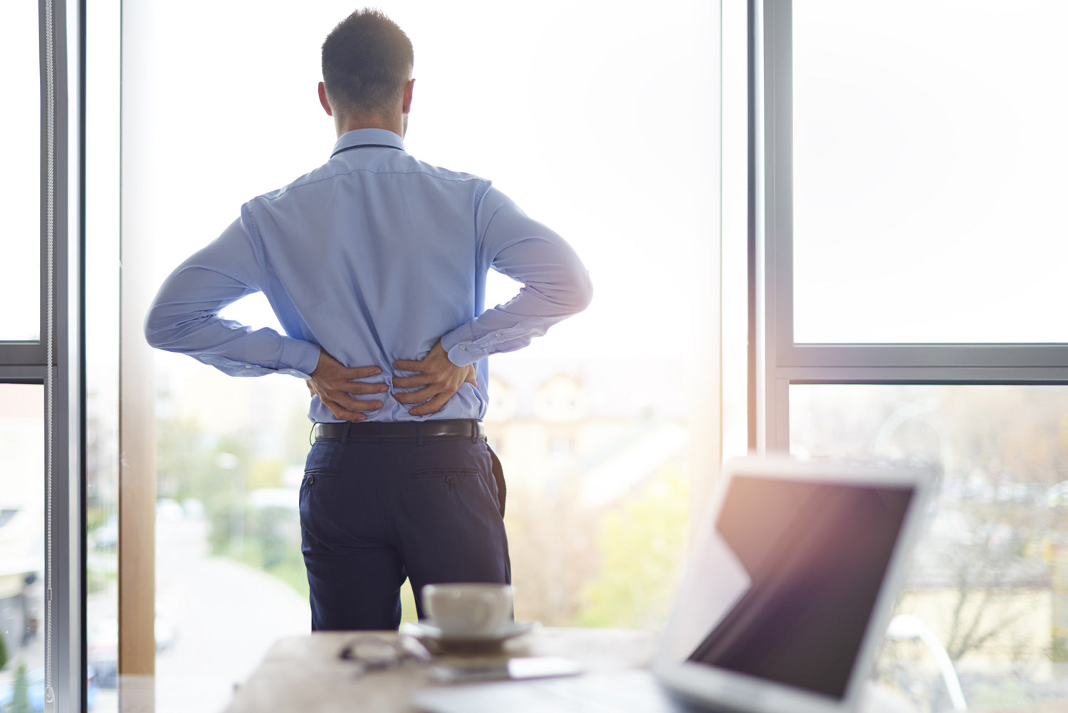 Personne ayant mal au dos derrière son bureau traditionnel