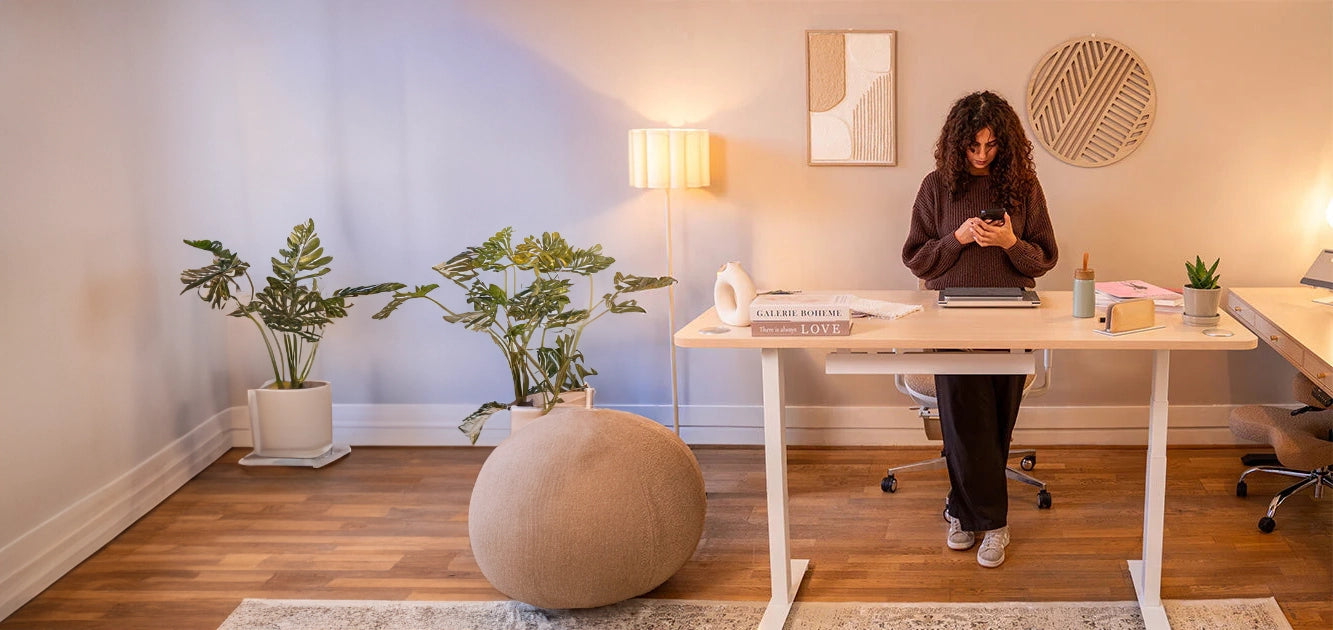Bureau assis-debout ergonomique KQUEO dans un bureau moderne avec une femme debout