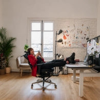 Femme installée dans une chaise de bureau ergonomique, les pieds posés sur un bureau assis-debout