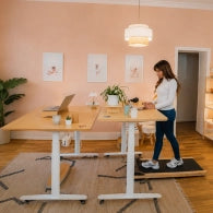 Femme travaillant debout sur un tapis de marche devant un bureau assis-debout en bois
